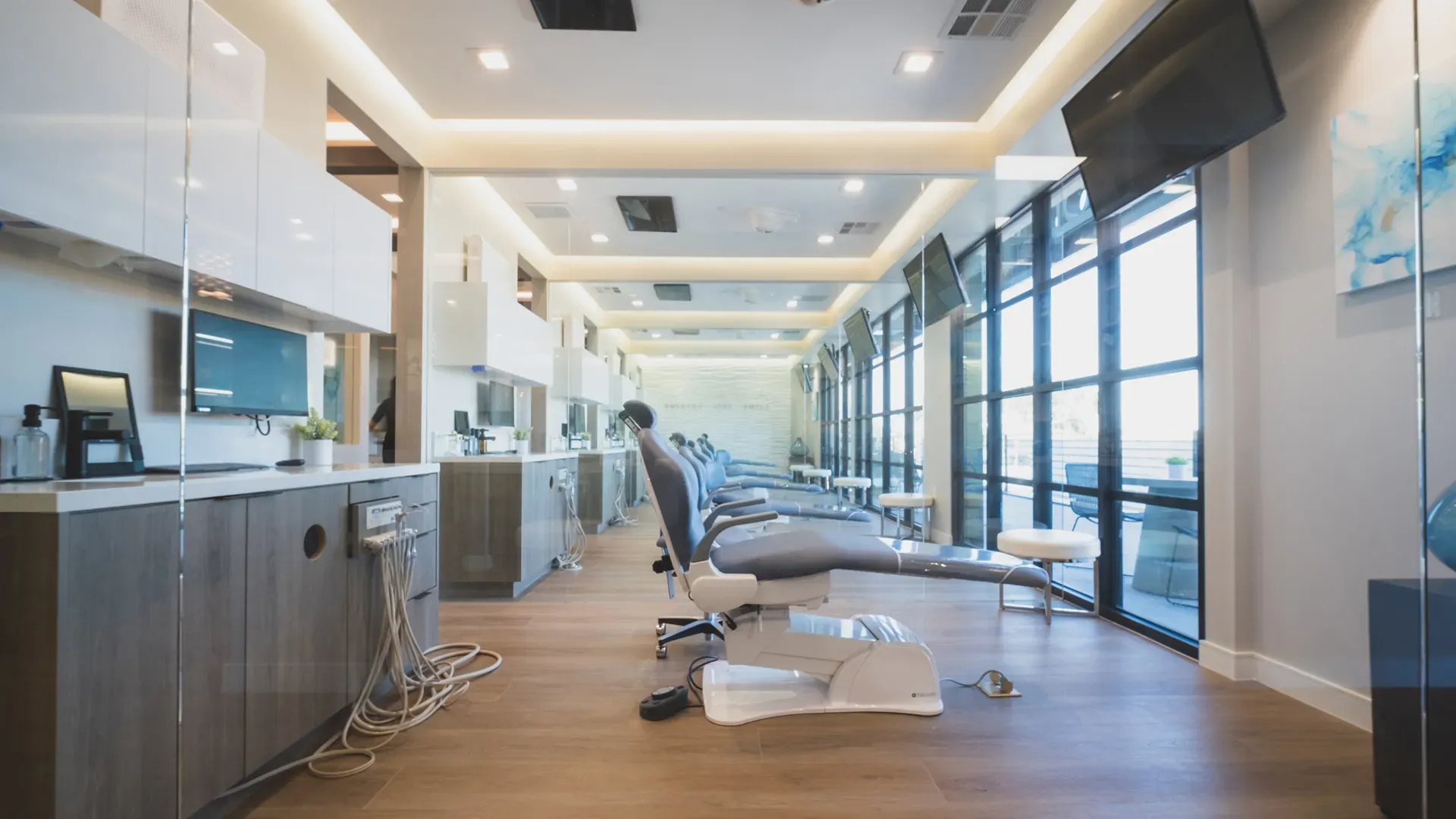 The clinical floor: treatment chairs in a row beside tall windows, each with a screen on the wall
